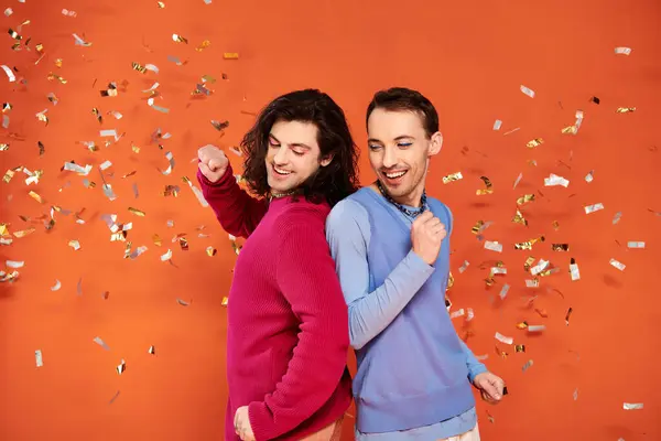 Glücklich gut aussehende schwule Freunde in stilvoller Kleidung mit Make-up posieren unter Konfettiregen, Stolz — Stockfoto