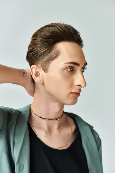 Un jeune queer pose fièrement avec un collier autour du cou dans un décor de studio, respirant confiance et fierté. — Photo de stock