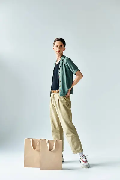Um jovem elegante confiantemente posa com sacos de compras contra um fundo branco. — Fotografia de Stock