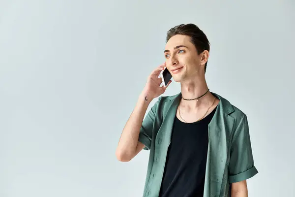 Una persona queer joven profundamente absorto en una llamada telefónica contra un fondo gris sereno. — Stock Photo