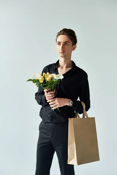 Un joven queer sostiene elegantemente una bolsa de papel llena de flores vibrantes, irradiando orgullo en un ambiente de estudio. — Stock Photo