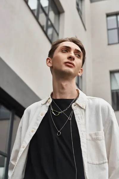 Um jovem elegante, exalando confiança, veste uma camisa branca e um colar com um toque rebelde.. — Fotografia de Stock