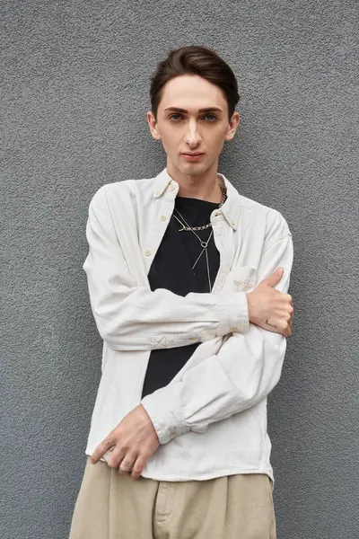 Uma jovem queer em trajes elegantes, encostada a uma parede em uma camisa branca, exalando confiança e orgulho. — Fotografia de Stock