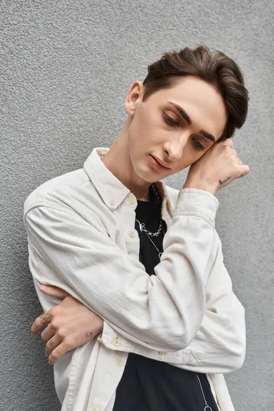 A young man in stylish attire leans against a wall, exuding a sense of rebellion and contemplation. — Stock Photo