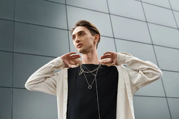 Elegantemente vestido joven queer posa con confianza, las manos apoyadas en los hombros en una muestra de orgullo y seguridad. — Stock Photo