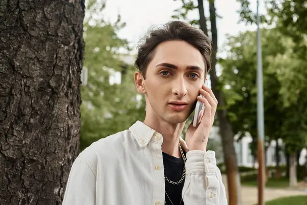 A young man, dressed stylishly, converses on a cellphone in a park setting. — Stock Photo