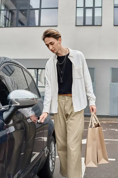Jovem queer individual em trajes elegantes descarregando sacos de compras de um carro estacionado ao lado de uma estrada. — Fotografia de Stock