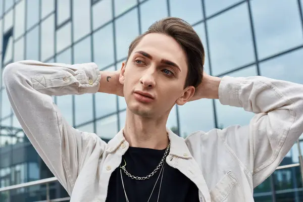 A stylishly dressed young man strikes a confident pose in front of a striking building, embodying pride and individuality. — Stock Photo