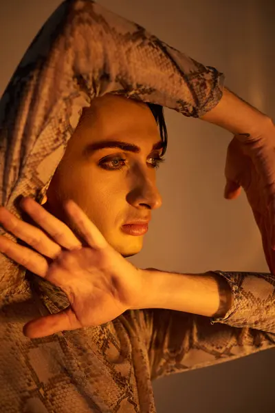 A young queer person in stylish attire strikes a powerful pose with hands in the air, expressing lgbt and pride. — Stock Photo