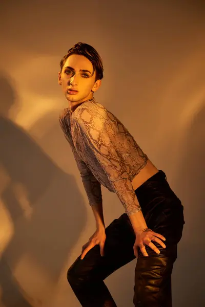Una joven queer en pantalones de cuero da una pose segura para la cámara mostrando su atuendo audaz y elegante. - foto de stock