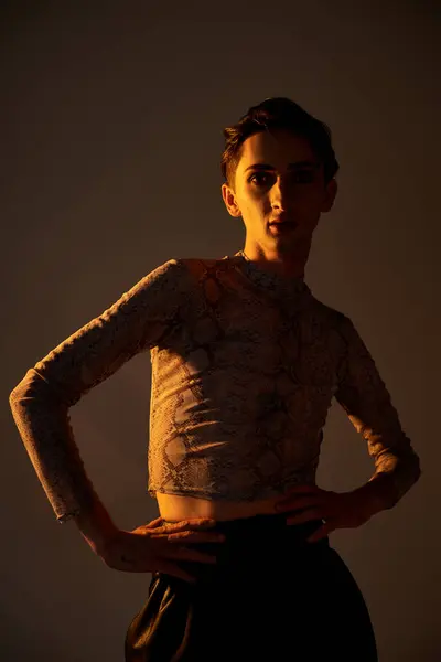 A young queer person strikes a stylish pose in front of a dark background, exuding confidence and pride. — Stock Photo