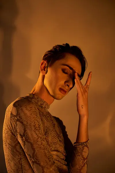 Un giovane uomo queer, vestito con stile, nel profondo del pensiero con la mano sul viso. — Foto stock