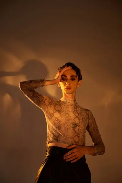 A young queer person in stylish attire stands before a mirror in a dimly lit room, admiring their reflection. — Stock Photo