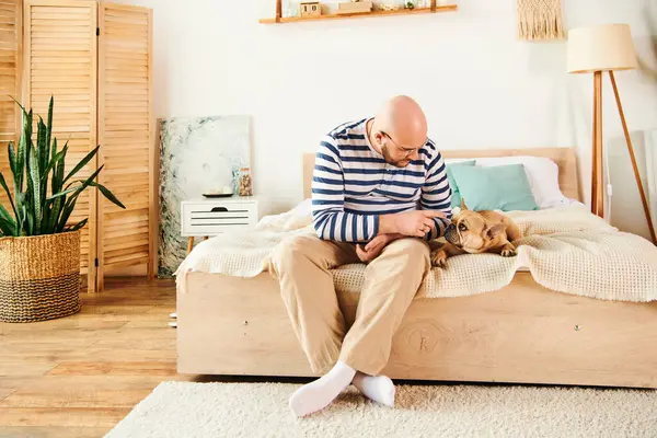 Handsome man sitting on bed, relaxing with loyal French Bulldog. — Stock Photo