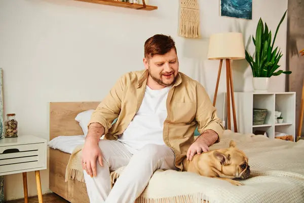 A handsome man relaxes on a bed with his loyal French Bulldog. — Stock Photo