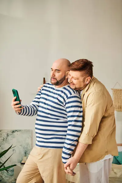 Una pareja gay tomando una selfie con un teléfono celular. - foto de stock