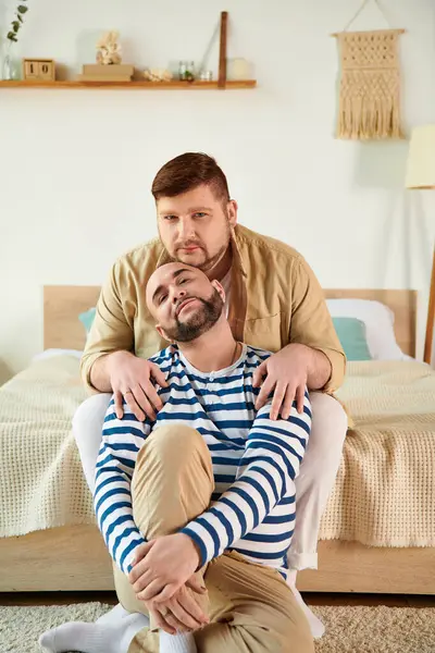 Двое мужчин обнимают друг друга у кровати в уютных одеждах. — стоковое фото