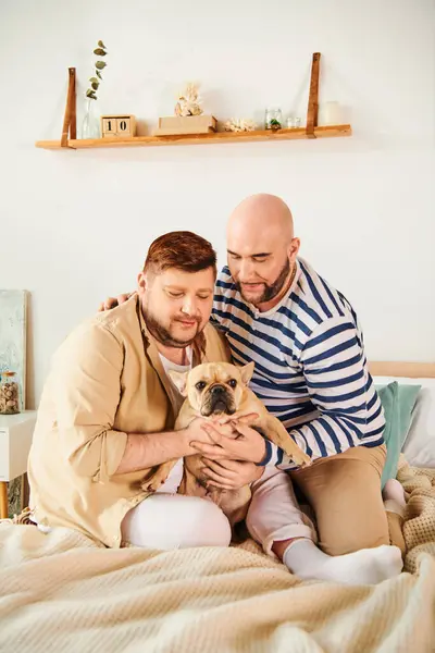 Man tenderly holds small bulldog on bed in cozy home setting. — Stock Photo