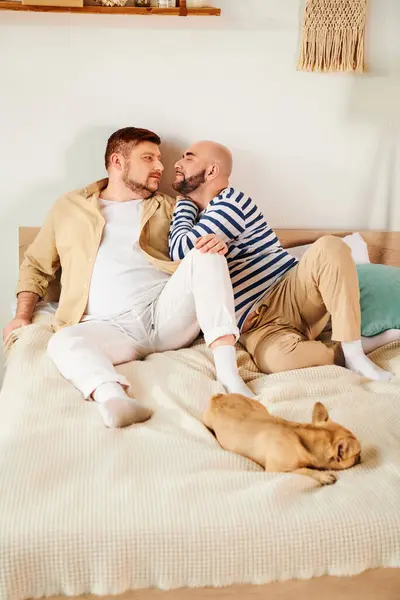 Два чоловіки лежали на ліжку зі своїм французьким бульдогом поруч з ними. — стокове фото