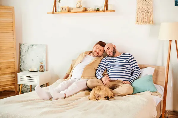 A gay couple, alongside their French Bulldog, lounging on a bed. — Stock Photo