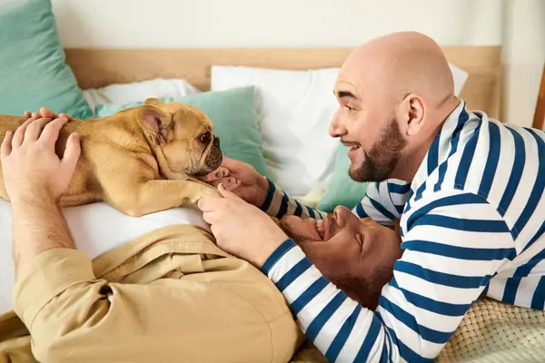 Zwei Männer entspannen sich im Bett mit ihrer französischen Bulldogge. — Stockfoto