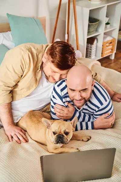 Two men, a French Bulldog, are lounging contentedly on a bed. — Stock Photo