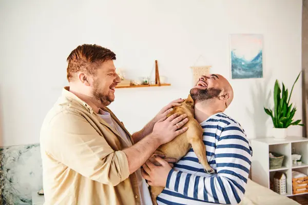 A man lovingly holds a French Bulldog in a cozy living room setting. — Stock Photo