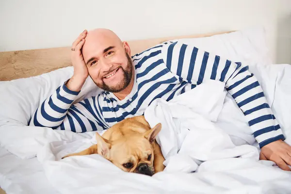 Ein Mann ruht friedlich im Bett mit seiner geliebten französischen Bulldogge neben ihm. — Stockfoto