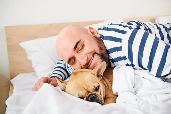 A man and his dog peacefully lie in bed together. — Stock Photo
