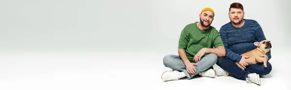 Two men sitting closely, engrossed in conversation, with a French Bulldog at their feet. — Stock Photo