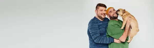 A man tenderly holds a French bulldog in his arms. — Stock Photo