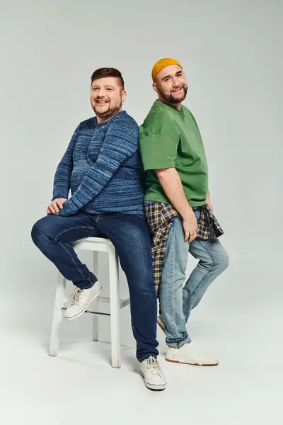 Two men pose together on stool. — Stock Photo