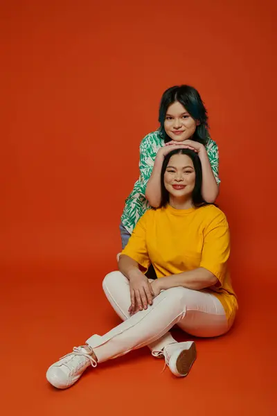 An Asian mother sitting on the ground next to her teenage daughter, sharing a moment of closeness and connection. — Stock Photo
