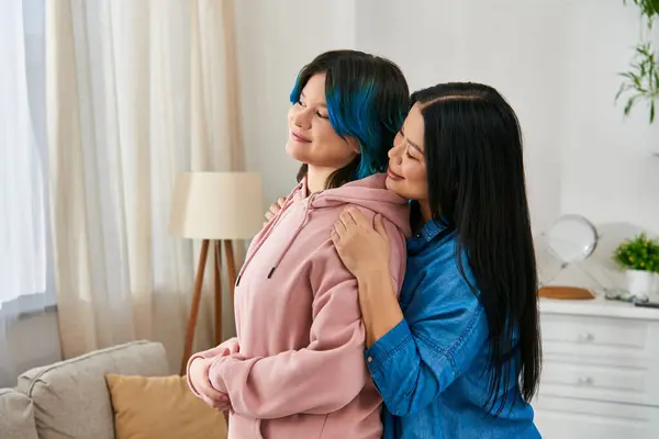 An Asian mother and her teenage daughter, in casual attire, standing together in a cozy living room. — Stock Photo