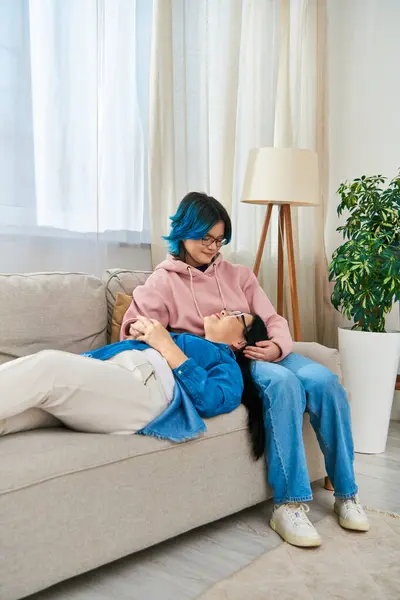 Uma mãe e uma filha, ambas asiáticas, relaxam juntas em um sofá em casa. — Fotografia de Stock