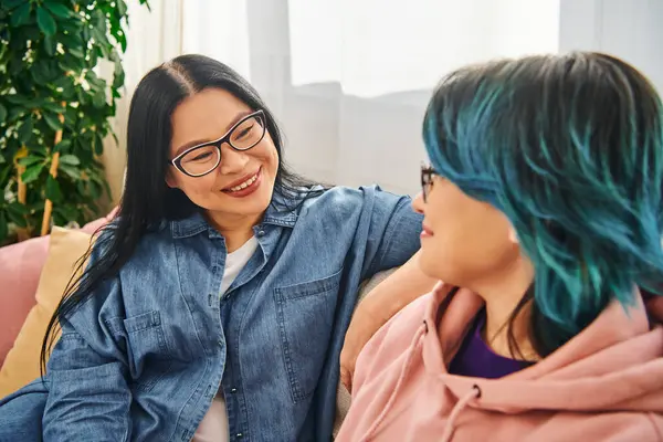 Asian mother and teenage daughter engage in heartfelt conversation on a cozy couch at home, creating a warm and loving atmosphere. — Stock Photo