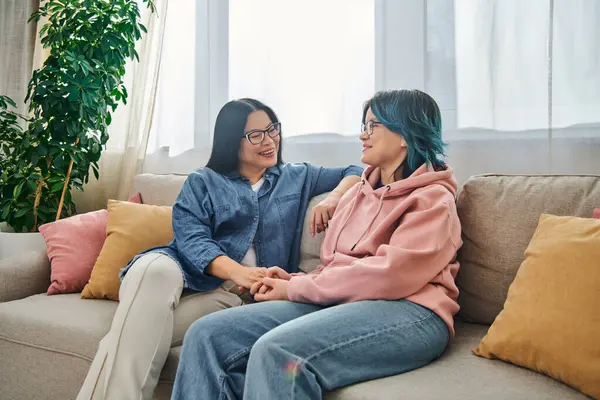 An Asian mother and her teenage daughter in casual wear having a heartfelt conversation while sitting on a cozy couch. — Stock Photo