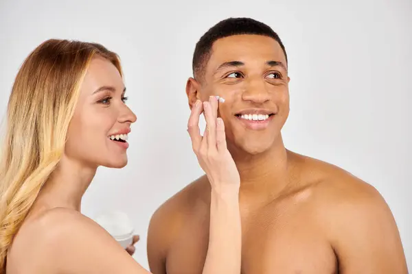 Man and woman lovingly apply face cream together. — Stock Photo