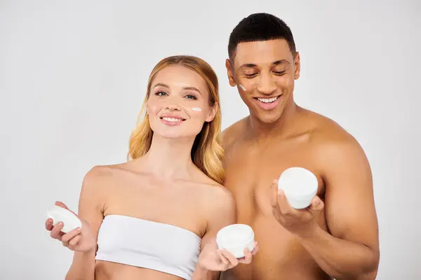 Trendy couple holding creams together during skin care routine. — Stock Photo
