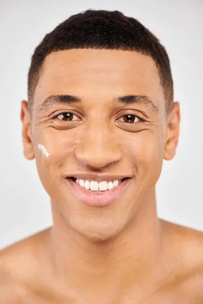 Jovem sorrindo com creme no rosto. — Fotografia de Stock