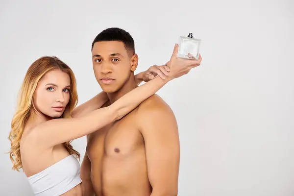 Stylish couple holding perfume bottle, enjoying a moment together. — Stock Photo