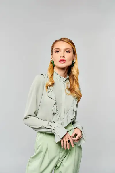 Chic woman wearing a green blouse and wide leg pants poses elegantly. — Stock Photo