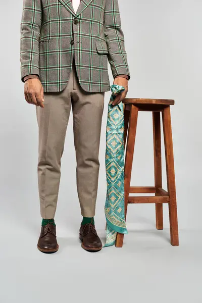 L'uomo elegante in giacca a quadri e cravatta si erge con fiducia su uno sgabello. — Foto stock