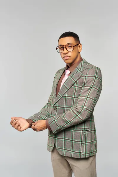 A man in glasses poses confidently in a stylish plaid blazer. — Stock Photo