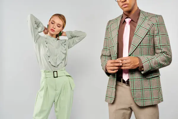A chic man and woman in plaid jackets and green pants pose together. — Stock Photo
