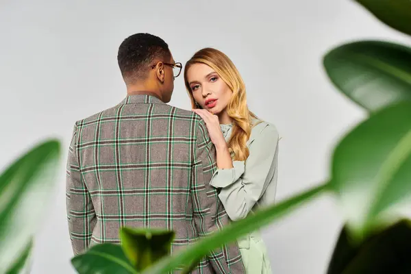 Um casal posando graciosamente na frente de uma planta exuberante. — Stock Photo