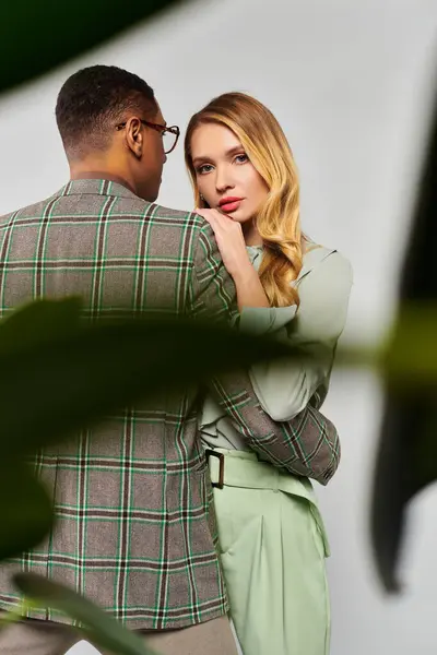 Man and woman hugging tenderly in front of a lush plant. — Stock Photo