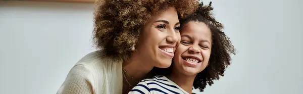 Una alegre madre e hija afroamericana comparten un momento de corazón, sonriéndose con amor y felicidad. - foto de stock