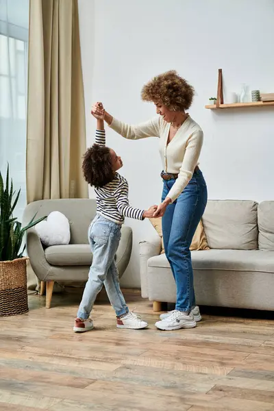 Uma feliz mãe e filha afro-americana dançando juntas em sua acolhedora sala de estar, compartilhando momentos especiais e criando memórias duradouras. — Fotografia de Stock