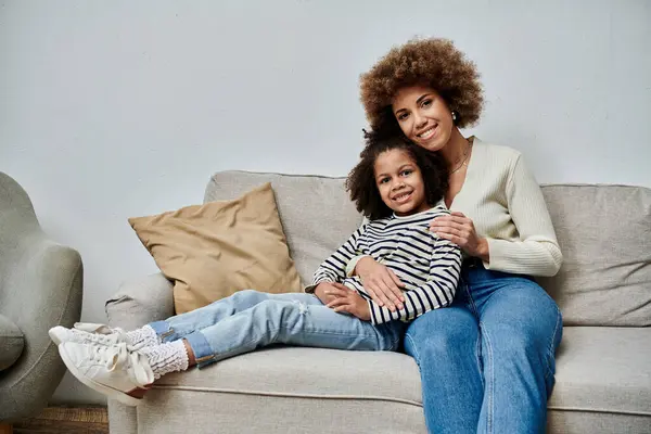 Happy African American mother and daughter spending quality time together, sitting comfortably on a couch. — Stock Photo